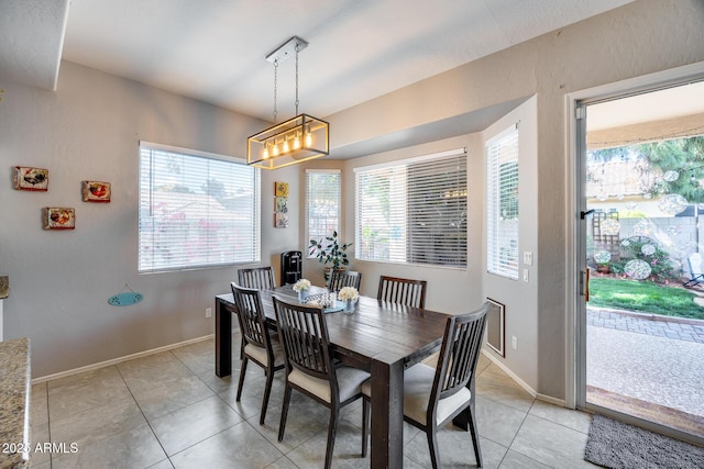 dining space with light tile patterned floors, baseboards, and a chandelier