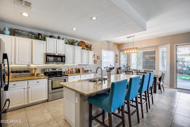 kitchen featuring appliances with stainless steel finishes, a sink, white cabinetry, healthy amount of natural light, and recessed lighting