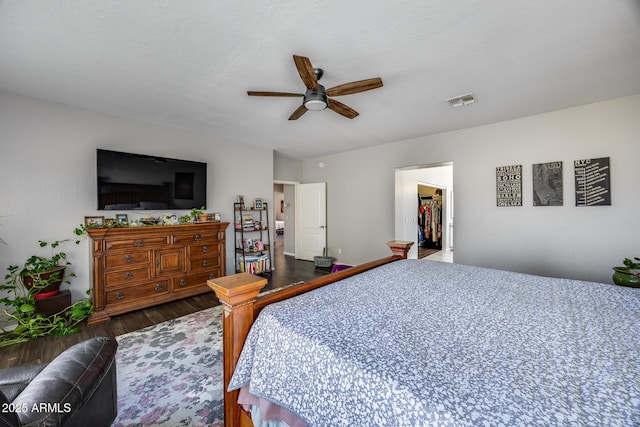 bedroom with wood finished floors, a ceiling fan, and a walk in closet