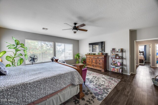 bedroom with wood finished floors, a textured ceiling, baseboards, and a ceiling fan