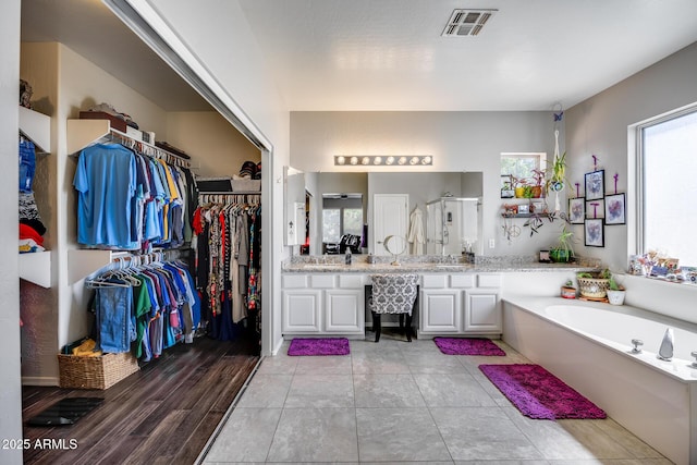 bathroom featuring vanity, a stall shower, a bath, and a spacious closet