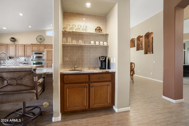 3507 N Snead Dr, Goodyear, AZ 85395 - indoor wet bar featuring double oven, decorative backsplash, light wood-style floors, baseboards, and recessed lighting