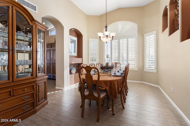 3507 N Snead Dr, Goodyear, AZ 85395 - dining space featuring a chandelier, wood finished floors, arched walkways, baseboards, and high vaulted ceiling