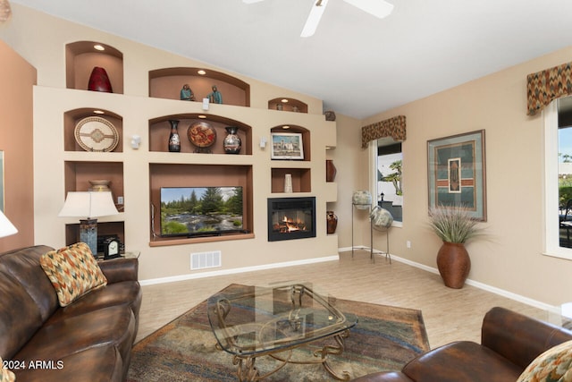 3507 N Snead Dr, Goodyear, AZ 85395 - living area with a glass covered fireplace, wood finished floors, healthy amount of natural light, ceiling fan, and vaulted ceiling