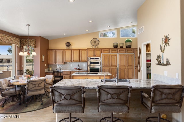3507 N Snead Dr, Goodyear, AZ 85395 - kitchen featuring a sink, stainless steel double oven, light stone countertops, lofted ceiling, and backsplash