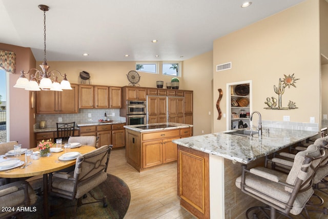 3507 N Snead Dr, Goodyear, AZ 85395 - kitchen with a sink, double oven, brown cabinets, light wood-style flooring, and a peninsula