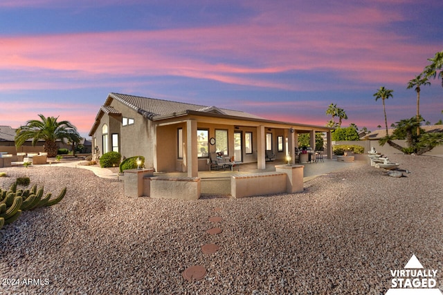 3507 N Snead Dr, Goodyear, AZ 85395 - back of house at dusk featuring a tile roof, a patio area, and stucco siding
