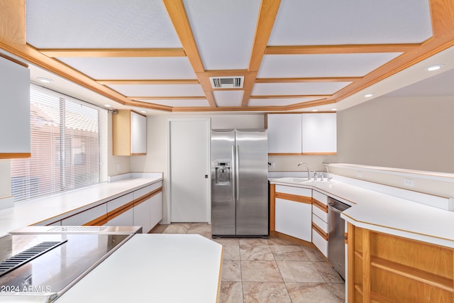 kitchen featuring coffered ceiling, beam ceiling, sink, white cabinetry, and appliances with stainless steel finishes