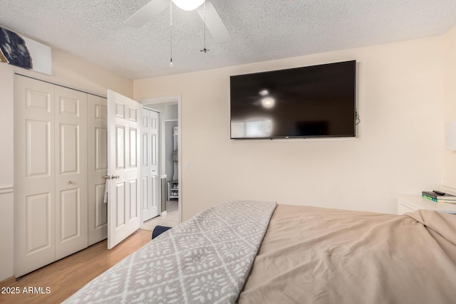 bedroom with a closet, a textured ceiling, a ceiling fan, and wood finished floors