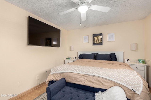 bedroom with a textured ceiling, a ceiling fan, baseboards, and wood finished floors