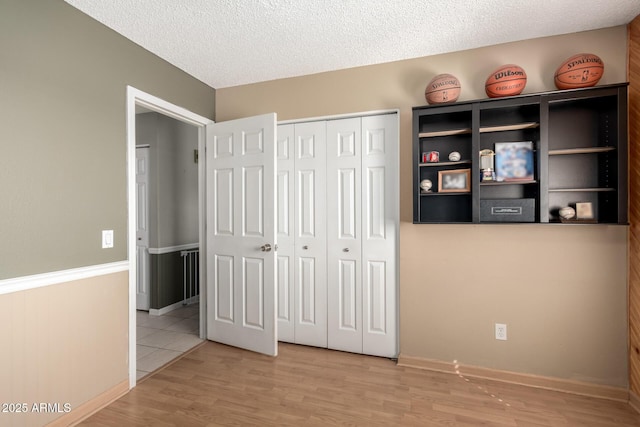 unfurnished bedroom featuring wood finished floors, a closet, and a textured ceiling