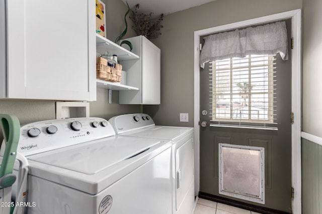 clothes washing area featuring washer and dryer, light tile patterned floors, and cabinet space