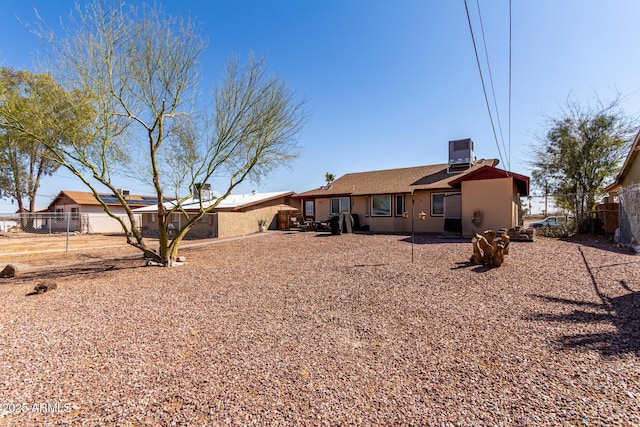 rear view of house featuring central AC unit and fence