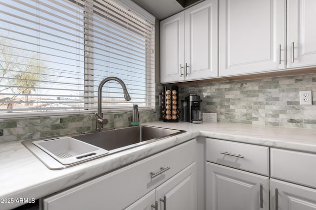 kitchen featuring tasteful backsplash, white cabinetry, and a sink