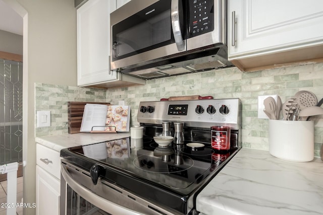 kitchen with white cabinets, light stone countertops, tasteful backsplash, and appliances with stainless steel finishes