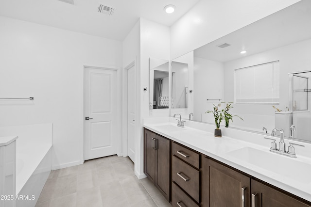 bathroom with a washtub, vanity, and tile patterned flooring