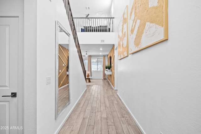 hallway with wood-type flooring and a towering ceiling