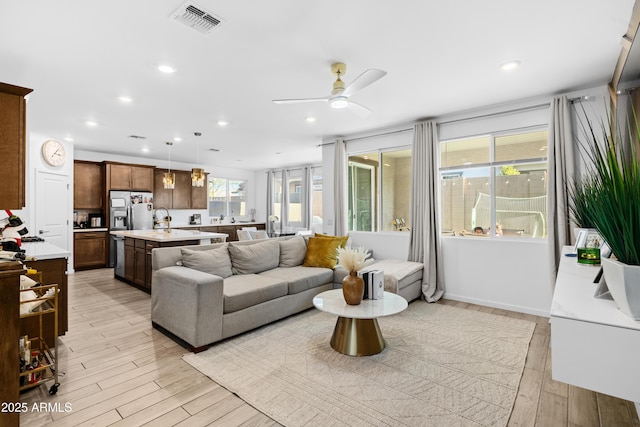 living room with ceiling fan, sink, light hardwood / wood-style flooring, and a wealth of natural light