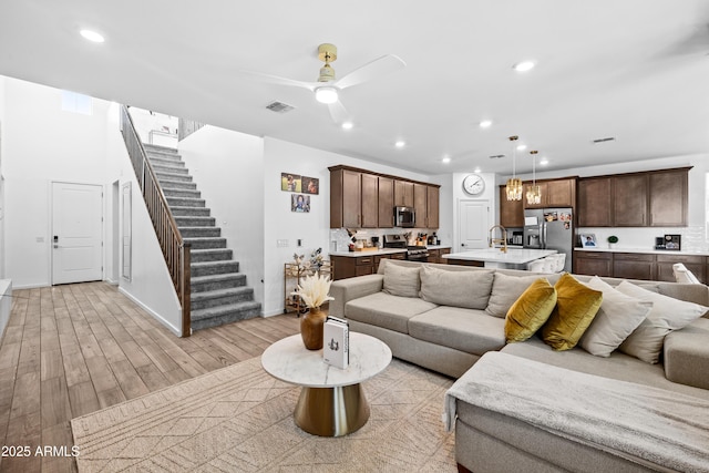 living room featuring ceiling fan, sink, and light hardwood / wood-style flooring