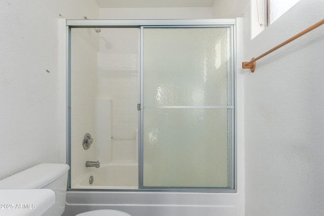 bathroom with bath / shower combo with glass door and toilet