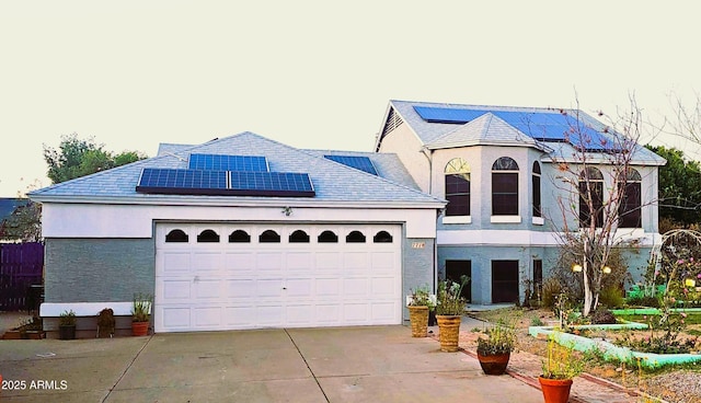 view of front of property with roof mounted solar panels, stucco siding, an attached garage, and concrete driveway