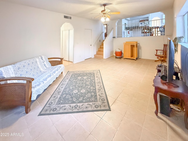 tiled living room featuring stairway, a ceiling fan, and visible vents