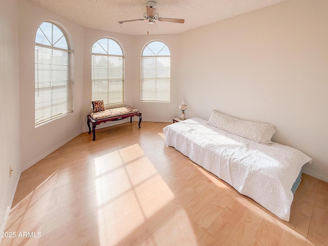 bedroom featuring light wood-type flooring, a textured ceiling, and a ceiling fan