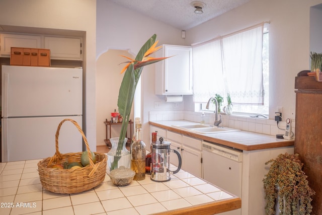 kitchen featuring tile counters, white cabinets, white appliances, and a sink