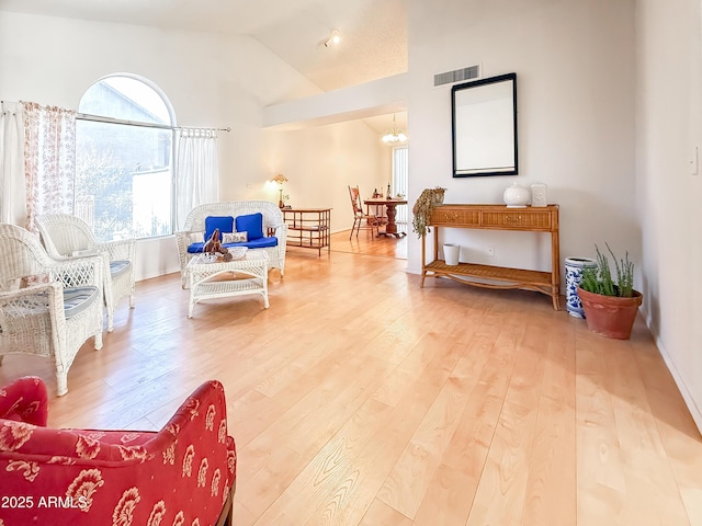 sitting room featuring visible vents, baseboards, light wood finished floors, lofted ceiling, and a chandelier