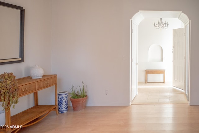 hall featuring light wood-style flooring and a notable chandelier