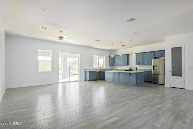 kitchen with ceiling fan, blue cabinetry, decorative light fixtures, a kitchen island, and stainless steel appliances