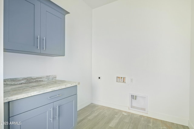 clothes washing area with electric dryer hookup, hookup for a washing machine, cabinets, and light hardwood / wood-style flooring