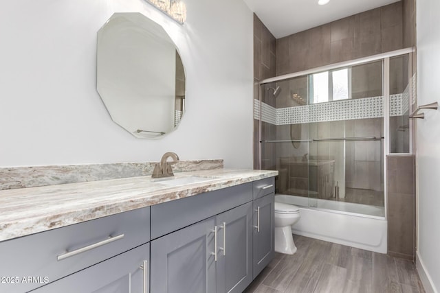 full bathroom with shower / bath combination with glass door, vanity, wood-type flooring, and toilet