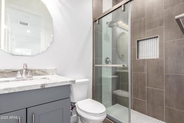 bathroom with vanity, a shower with shower door, and toilet