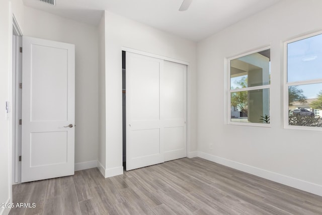 unfurnished bedroom with light hardwood / wood-style flooring, a closet, and ceiling fan