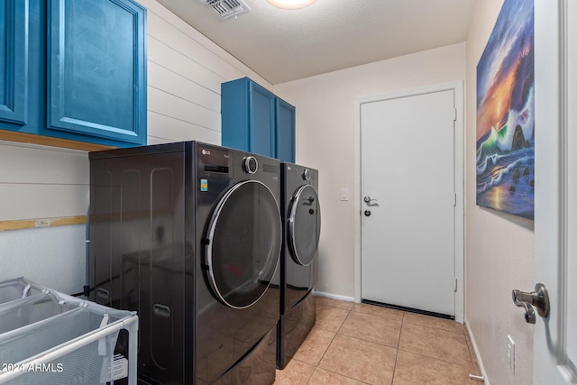 laundry area featuring separate washer and dryer, light tile patterned floors, cabinets, and a textured ceiling