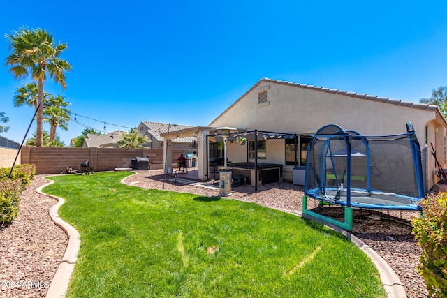 back of property featuring a patio area, a hot tub, a trampoline, a lawn, and a pergola