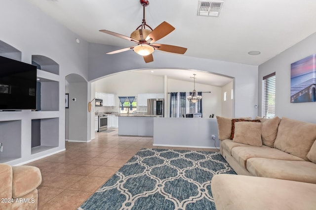 living room featuring lofted ceiling, ceiling fan with notable chandelier, built in features, and light tile patterned flooring