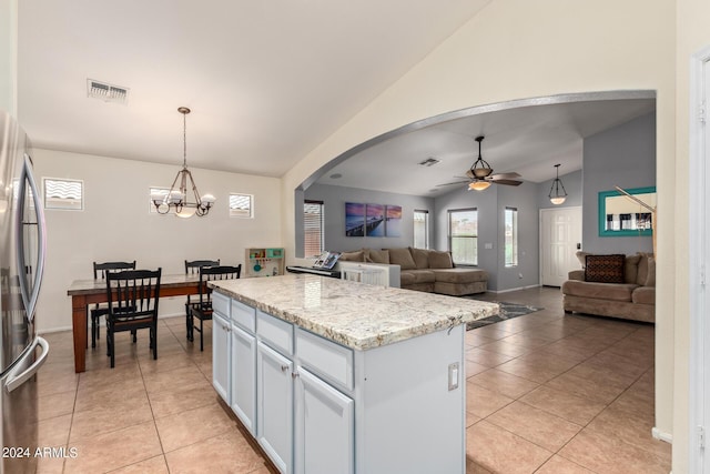 kitchen featuring decorative light fixtures, stainless steel fridge, white cabinets, and a kitchen island