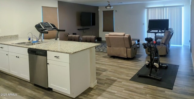 kitchen featuring light wood-style flooring, a peninsula, stainless steel dishwasher, white cabinets, and a sink