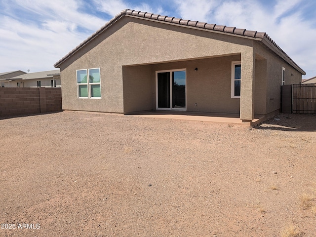 rear view of property with a patio, fence, a tile roof, and stucco siding