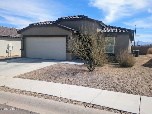 view of front of property featuring a tile roof, a garage, driveway, and stucco siding