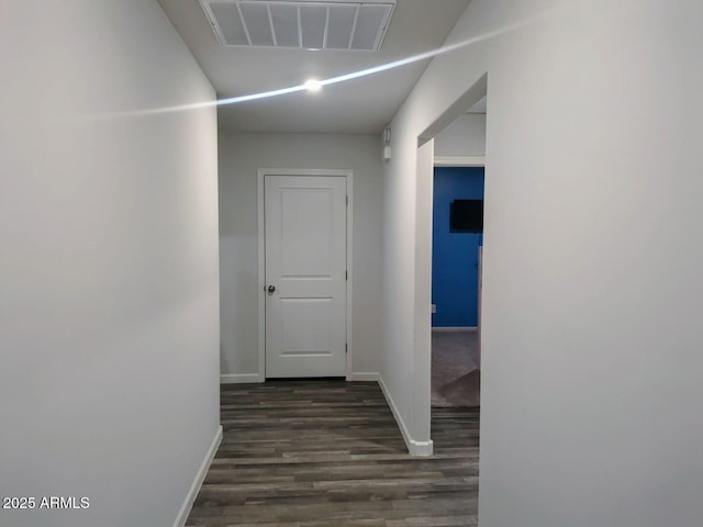 hall with dark wood-type flooring, baseboards, and visible vents