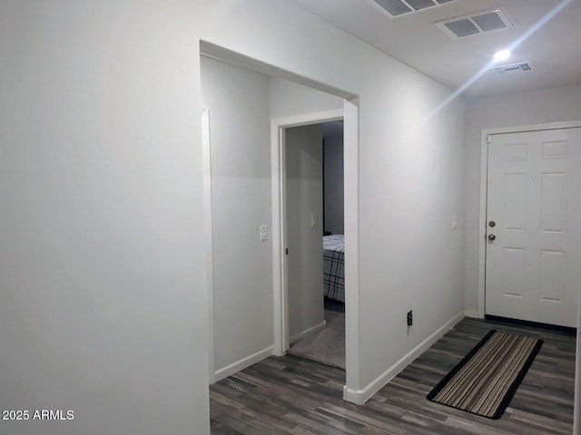 corridor featuring dark wood-style floors, visible vents, and baseboards