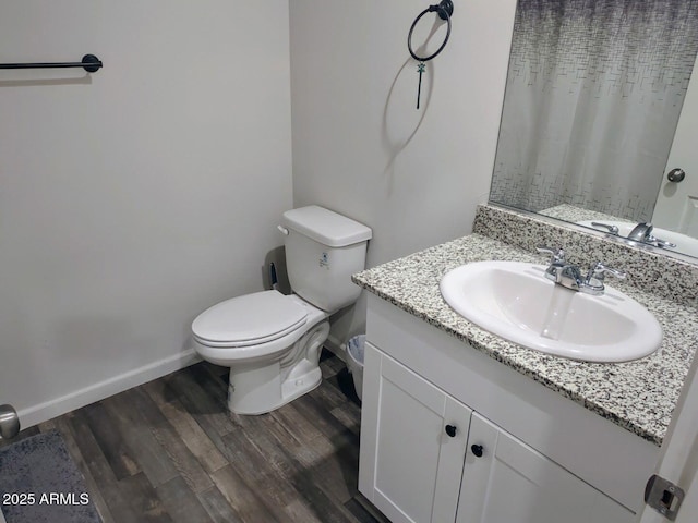 bathroom featuring vanity, toilet, wood finished floors, and baseboards