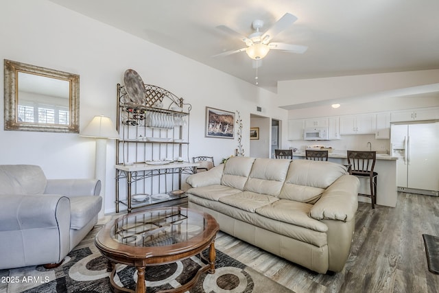 living room featuring hardwood / wood-style flooring, ceiling fan, and vaulted ceiling