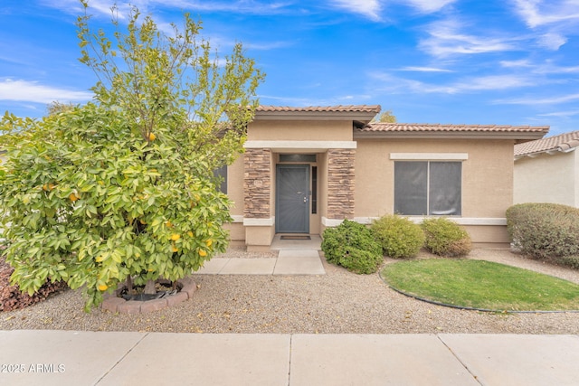 doorway to property featuring stone siding, a tiled roof, and stucco siding