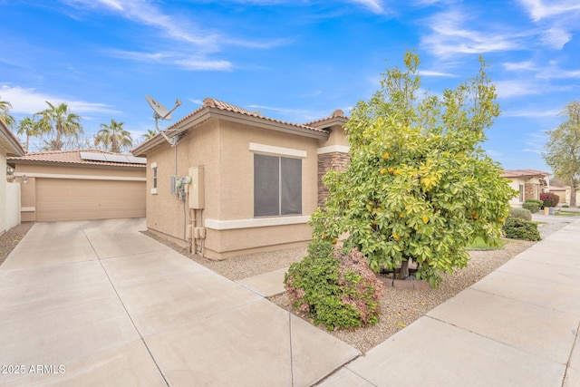 view of home's exterior featuring a garage, concrete driveway, a tile roof, and stucco siding