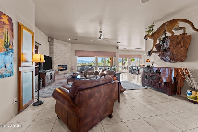 20910 W Cattle Iron Dr, Wickenburg, AZ 85390 - living area featuring light tile patterned flooring, a stone fireplace, visible vents, and ceiling fan