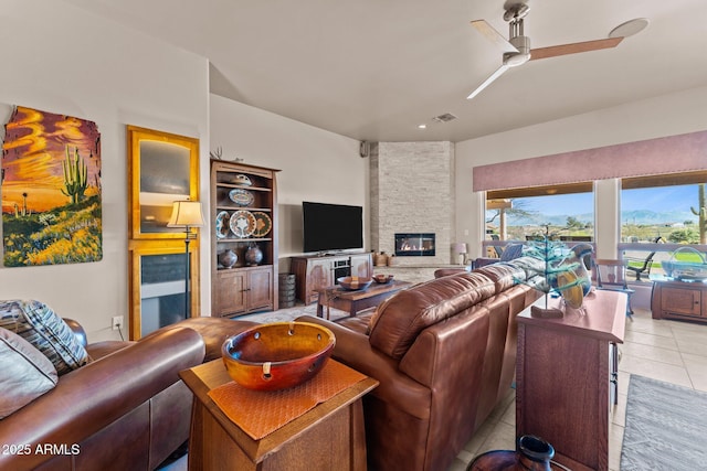 20910 W Cattle Iron Dr, Wickenburg, AZ 85390 - living room with light tile patterned flooring, visible vents, a fireplace, and a ceiling fan